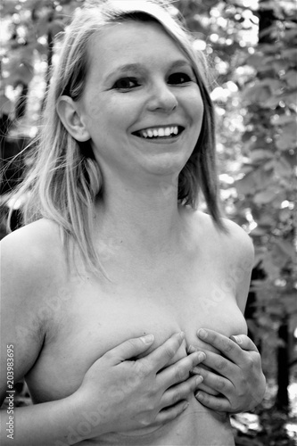 black and white photo of a smiling blonde, covering her breasts with her hands
