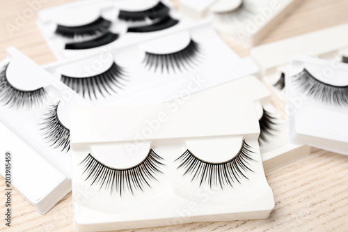 Different types of false eyelashes in packs on wooden background