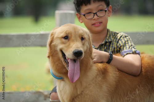 Asian boy playing with puppy dog golden retreiver in park