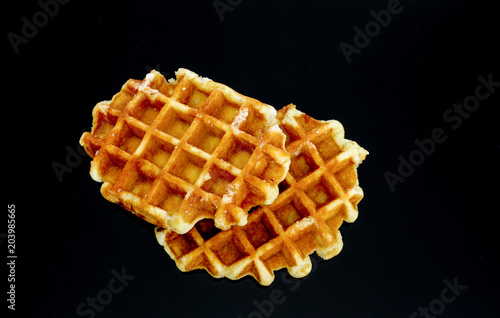 Two golden waffles on a black background