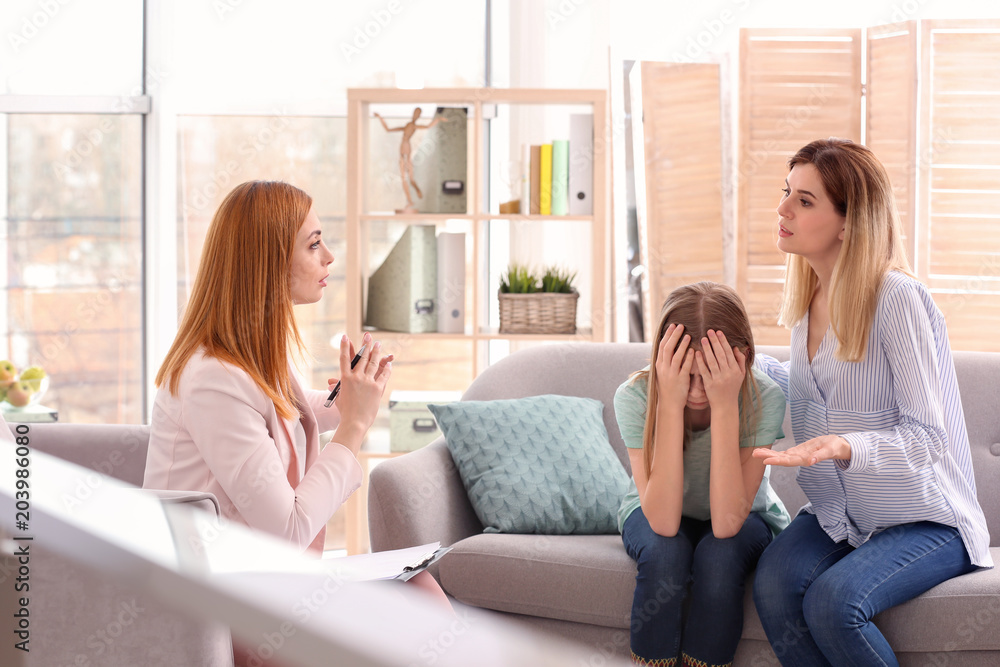 Young female psychologist working with teenage girl and her mother in office Young female psychologist working with teenage girl and her mother in office