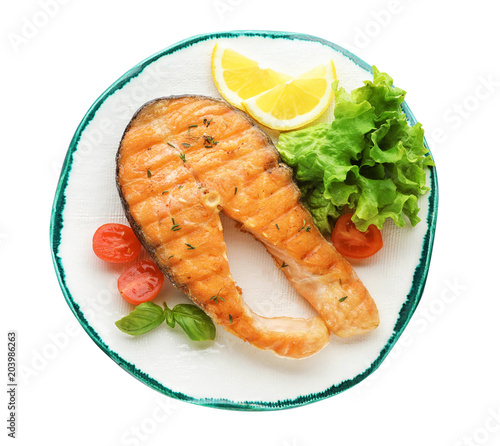 Plate with tasty salmon steak on white background