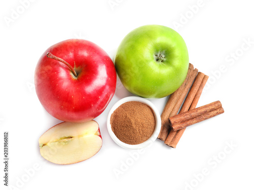 Fresh apples with cinnamon sticks and powder on white background