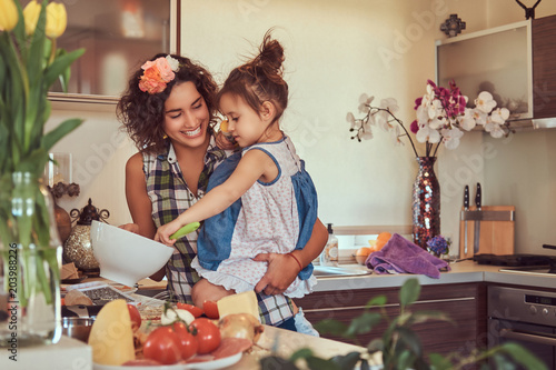Beautiful Hispanic mother teaches her cute little daughter prepare pizza in the kitchen. photo