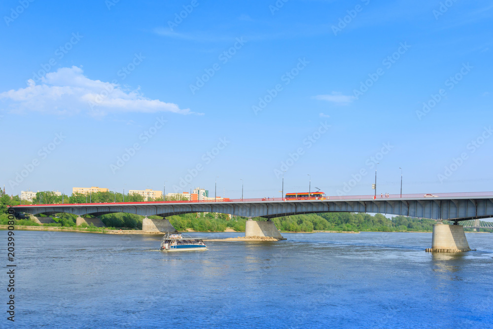 Touristic cruise boat sailing on the Vistula River under the Slasko-Dabrowski Bridge in Warsaw on a sunny day