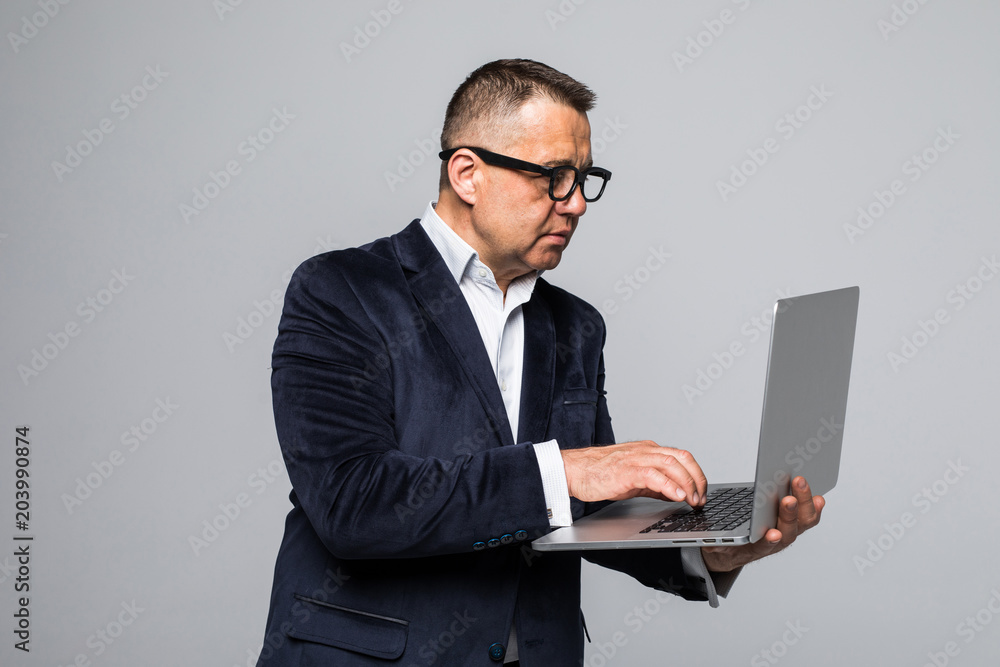 Senior man executive standing with open laptop isolated against white background Senior man executive standing with open laptop isolated against white background