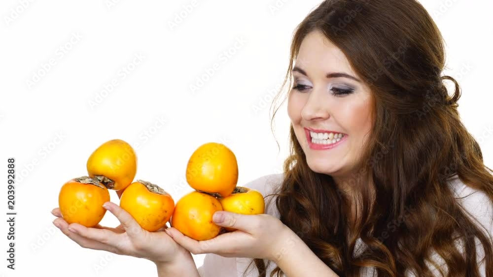 Woman toothy smile brunette girl holding many persimmon kaki fruits in hands, isolated on white. Healthy eating, vegetarian food, diet concept. Woman toothy smile brunette girl holding many persimmon kaki fruits in hands, isolated on white. Healthy eating, vegetarian food, diet concept.