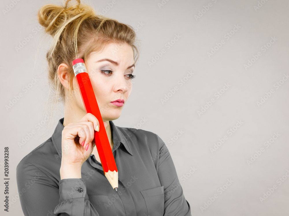Woman confused thinking, big pencil in hand Woman confused thinking, big pencil in hand