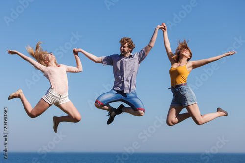 Carefree friends jumping by sea ocean water.