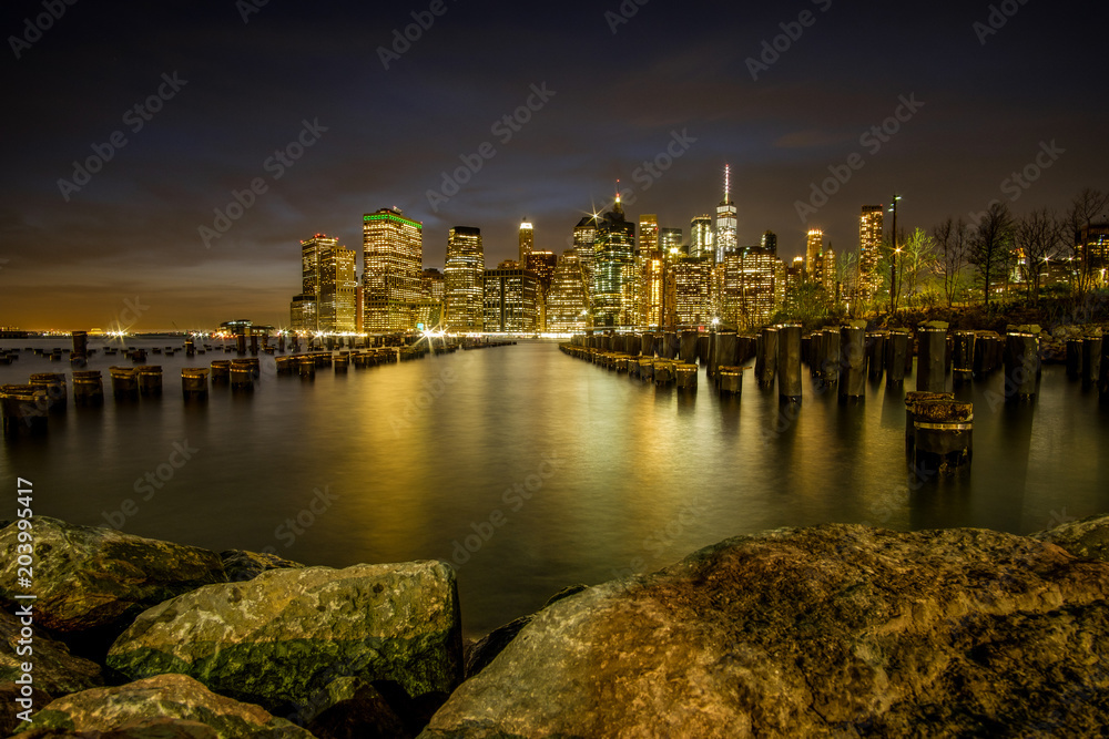 Night view of Manhattan skyline with city lights reflected in the water of the Hudson river. New York, USA.