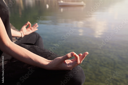 Woman meditating near mountain lake close up