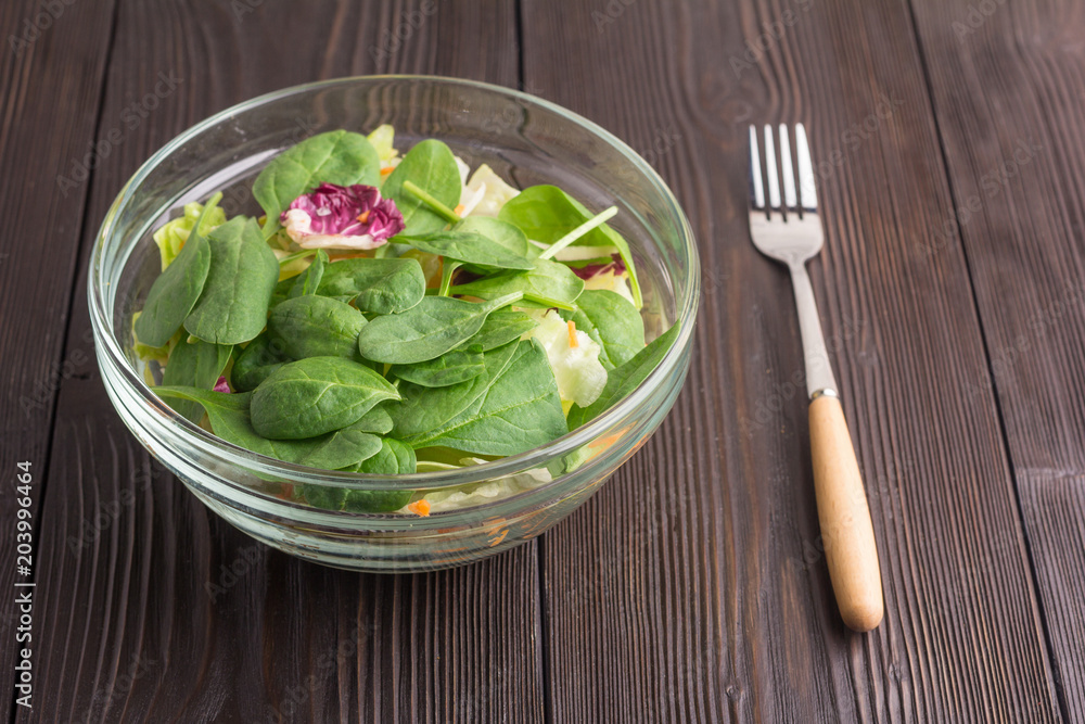 Fresh green salad with spinach, arugula, romaine and lettuce in bowl on brown wooden background Fresh green salad with spinach, arugula, romaine and lettuce in bowl on brown wooden background