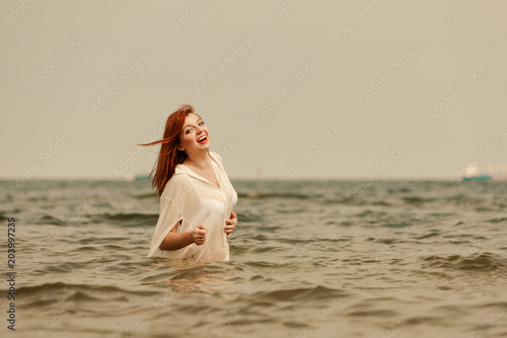 Redhead woman playing in water during summertime Redhead woman playing in water during summertime