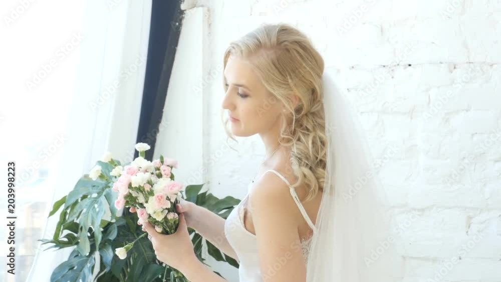 Young woman, bride posing for photo in studio, natural light, blonde beautiful girl is posing Young woman, bride posing for photo in studio, natural light, blonde beautiful girl is posing