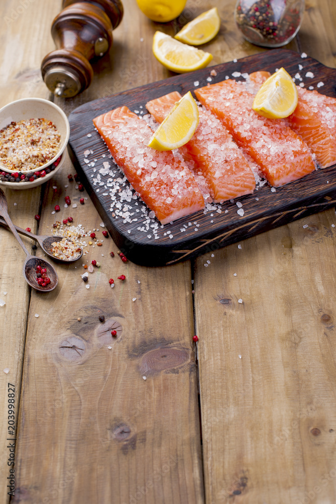 Salmon is sliced  and sprinkled with salt and spices, on a wooden board. Free space for text. Seafood