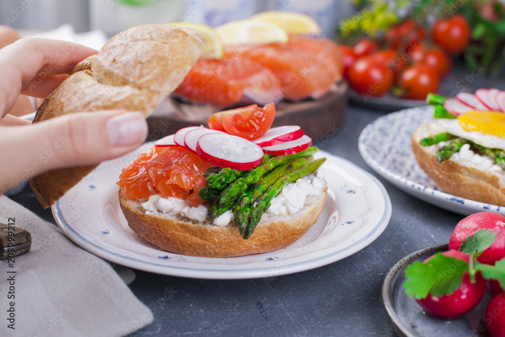Bread with cheese, radish, salmon and asparagus, in a woman's hand. Different Healthy Eating. Delicious breakfast for the family. Food in the Netherlands