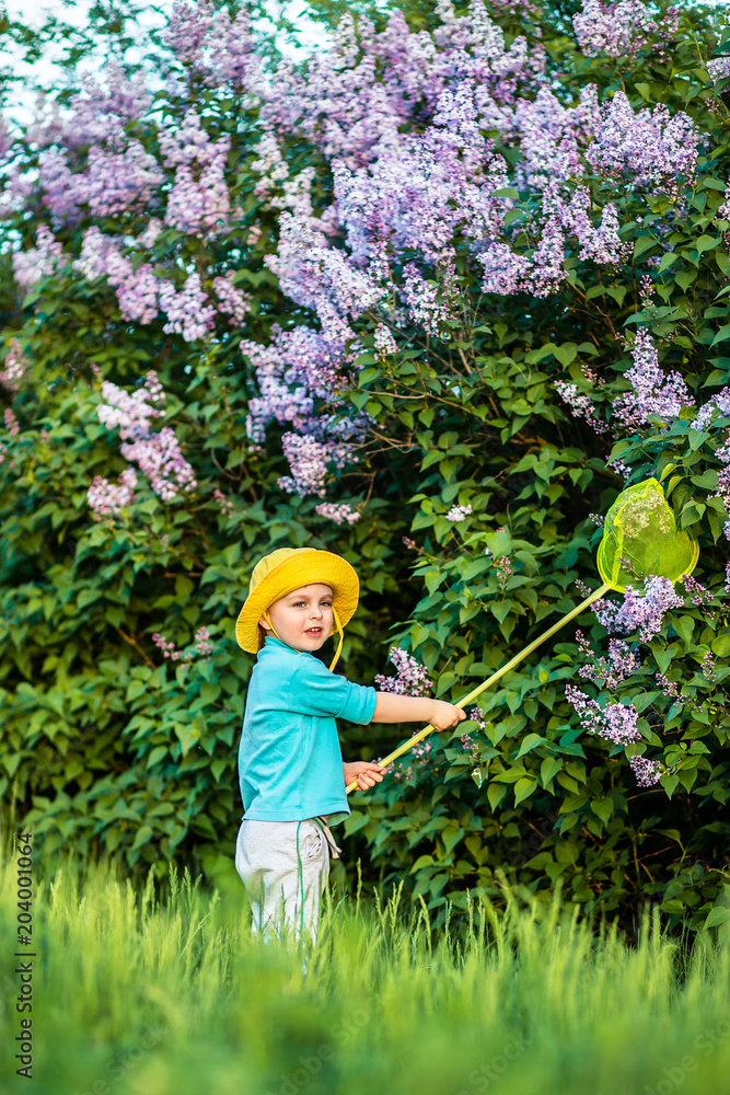 A charming kid playing with a scoop on a meadow in a warm and sunny summer or spring day. A charming kid playing with a scoop on a meadow in a warm and sunny summer or spring day.