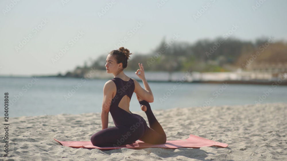 Young beautiful woman practicing yoga on the beach at sunny day. Healthy active lifestyle concept