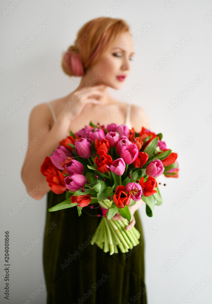 Beautiful woman hold bouquet of red and pink tulip flowers happy smiling on grey 