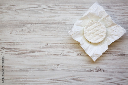 Camembert cheese on paper on white wooden background. Food for wine. From above. Top view, copy space