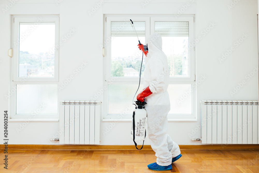 Exterminator in work wear spraying pesticide or insecticide with sprayer. Exterminator in work wear spraying pesticide or insecticide with sprayer.