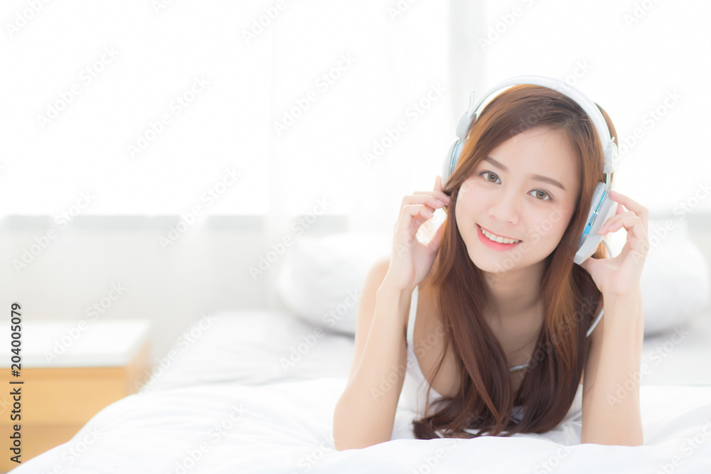 Naklejka premium Beautiful asian young woman enjoy listen music with headphone while lying in bedroom, relax girl with earphone internet online, leisure and technology concept.
