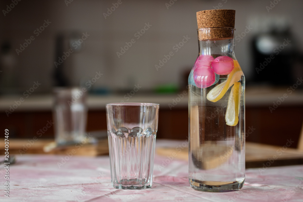 Fresh water with lemon. A refreshing drink in a glass container standing in the kitchen. Fresh water with lemon. A refreshing drink in a glass container standing in the kitchen.