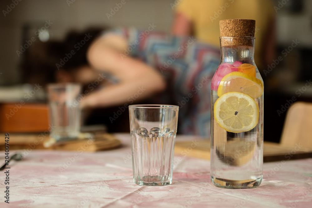 Fresh water with lemon. A refreshing drink in a glass container standing in the kitchen. Fresh water with lemon. A refreshing drink in a glass container standing in the kitchen.