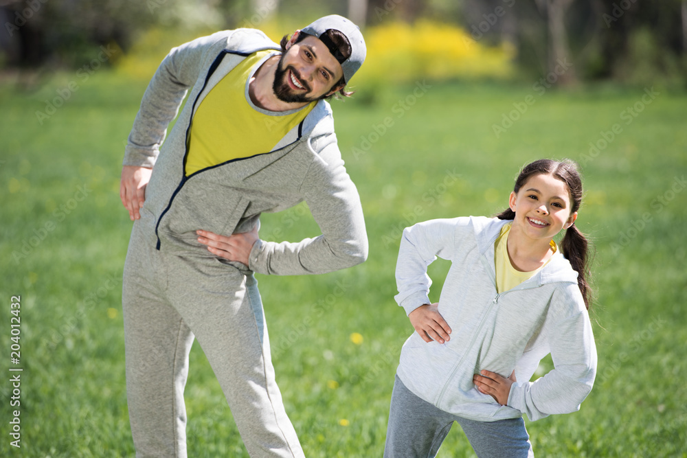 smiling father and daughter doing physical exercise in park smiling father and daughter doing physical exercise in park