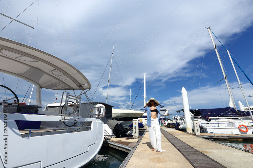 Fototapeta premium Mix Race Tanned skin Woman walk along Luxury Yachts in Marina Bay Club