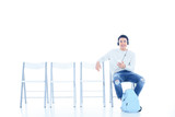 happy teenage student boy listening music while sitting on chair isolated on white