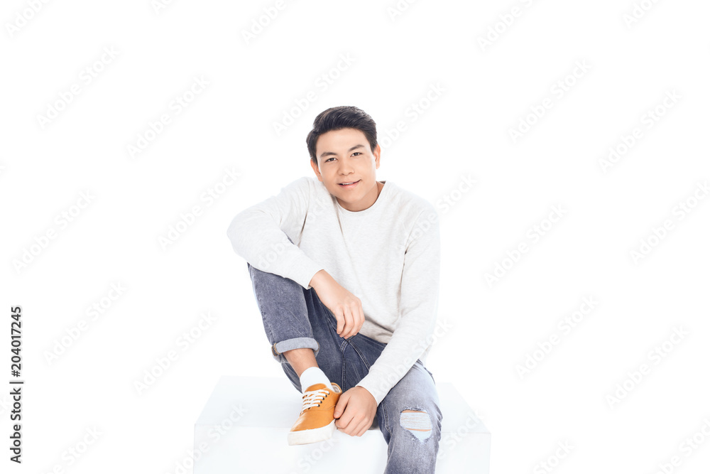 teen asian student boy sitting on white cube and looking at camera isolated on white teen asian student boy sitting on white cube and looking at camera isolated on white