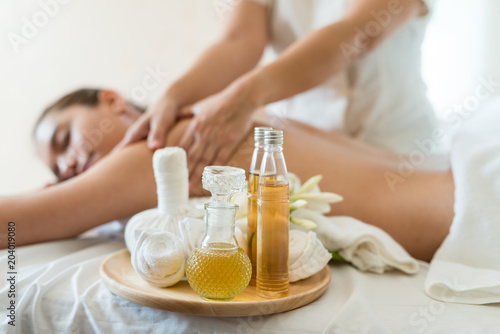 Bottle of essential oil on a wooden tray. background Young beautiful Asian woman relaxing in the spa massage
