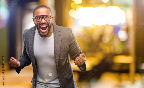 Фотография African american man with beard happy and excited celebrating victory expressing big success, power, energy and positive emotions