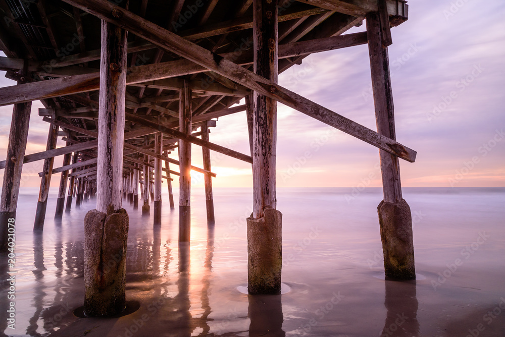 a warm autumn sun sets over a california coast pier. Memories of summer and play