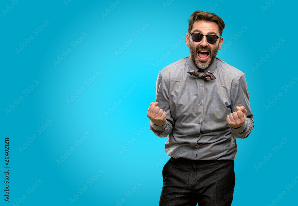 Middle age man, with beard and bow tie happy and excited celebrating victory expressing big success, power, energy and positive emotions. Celebrates new job joyful Middle age man, with beard and bow tie happy and excited celebrating victory expressing big success, power, energy and positive emotions. Celebrates new job joyful