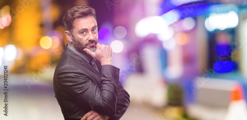 Middle age man, with beard and bow tie thinking thoughtful with smart face at night club