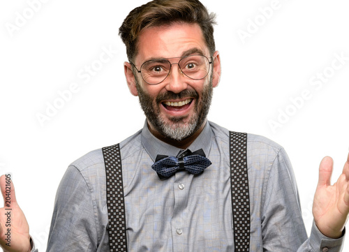Middle age man, with beard and bow tie happy and surprised cheering expressing wow gesture isolated over white background © Krakenimages.com