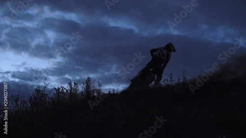Motocross racer start riding at his dirt bike kicking up dirt and dust at night. Side view Slow motion 4k
