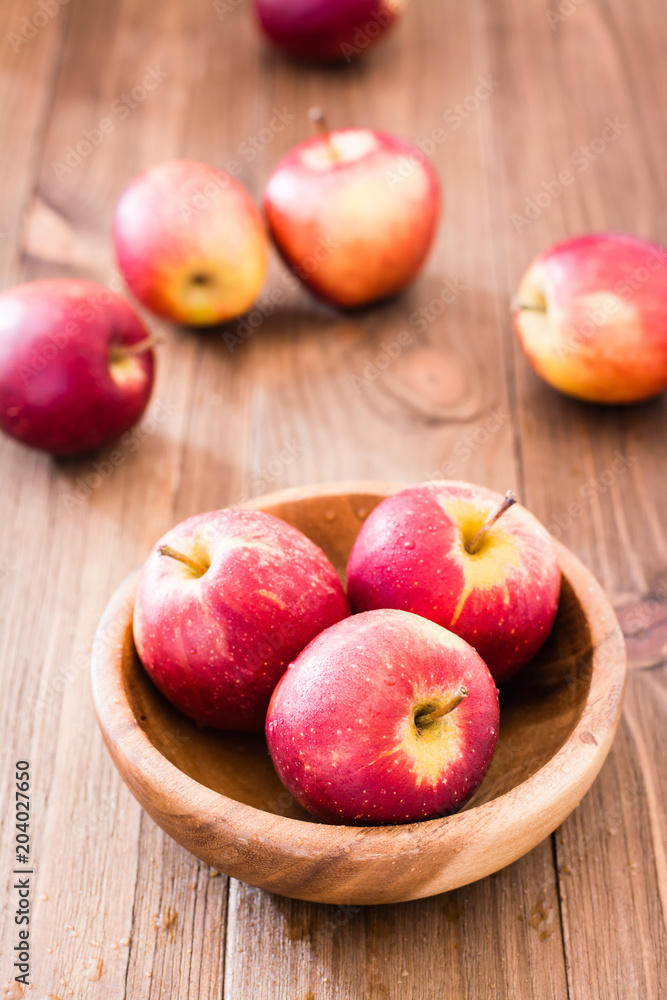 Red ripe apples in a wooden plate and on a wooden table Red ripe apples in a wooden plate and on a wooden table