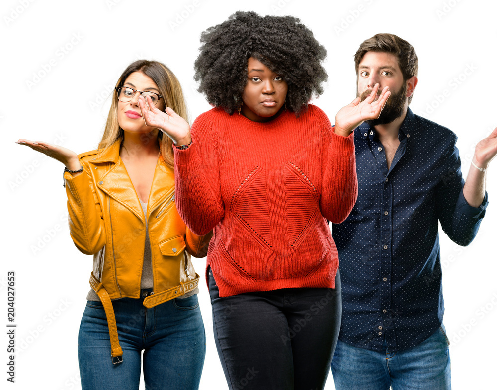 Group of three young men and women doubt expression, confuse and wonder concept, uncertain future shrugging shoulders Group of three young men and women doubt expression, confuse and wonder concept, uncertain future shrugging shoulders
