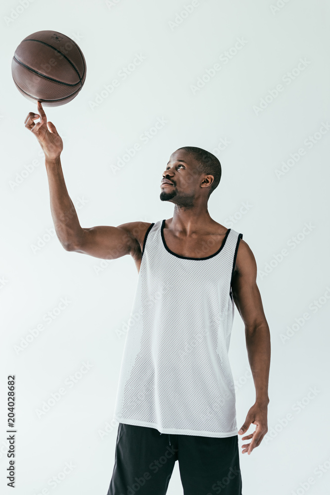 athletic african american basketball player spinning ball on finger, isolated on white
