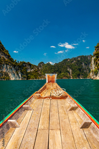 Traditional boat on a beautiful lake surrounded by towering cliffs and jungle
