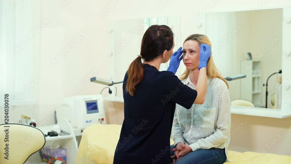 Cosmetologist preparing woman for eyebrow permanent makeup procedure Cosmetologist preparing woman for eyebrow permanent makeup procedure