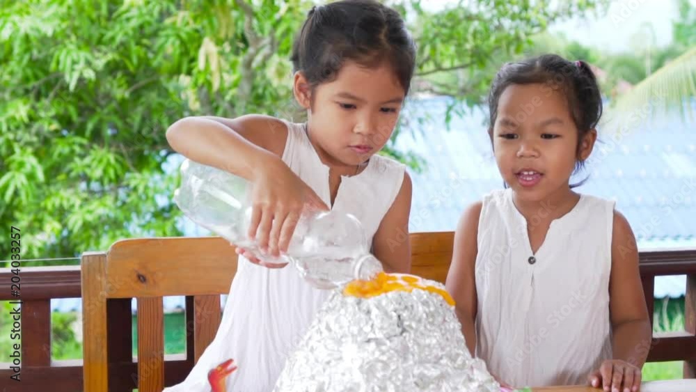 Two asian little girls do the baking soda and vinegar volcano