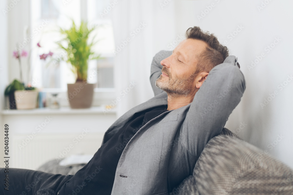Mature man wearing grey jacket relaxing on sofa Mature man wearing grey jacket relaxing on sofa