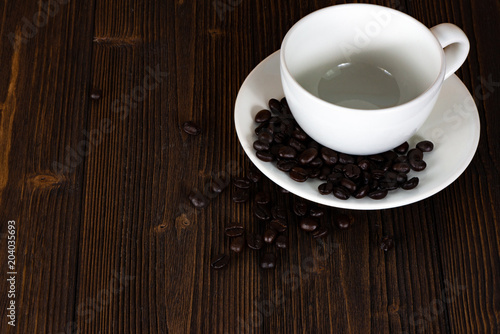 Roasted coffee beans with white cup on white wood table. coffee background with copy space...Roasted coffee beans with white cup on dark brown wood table. coffee background