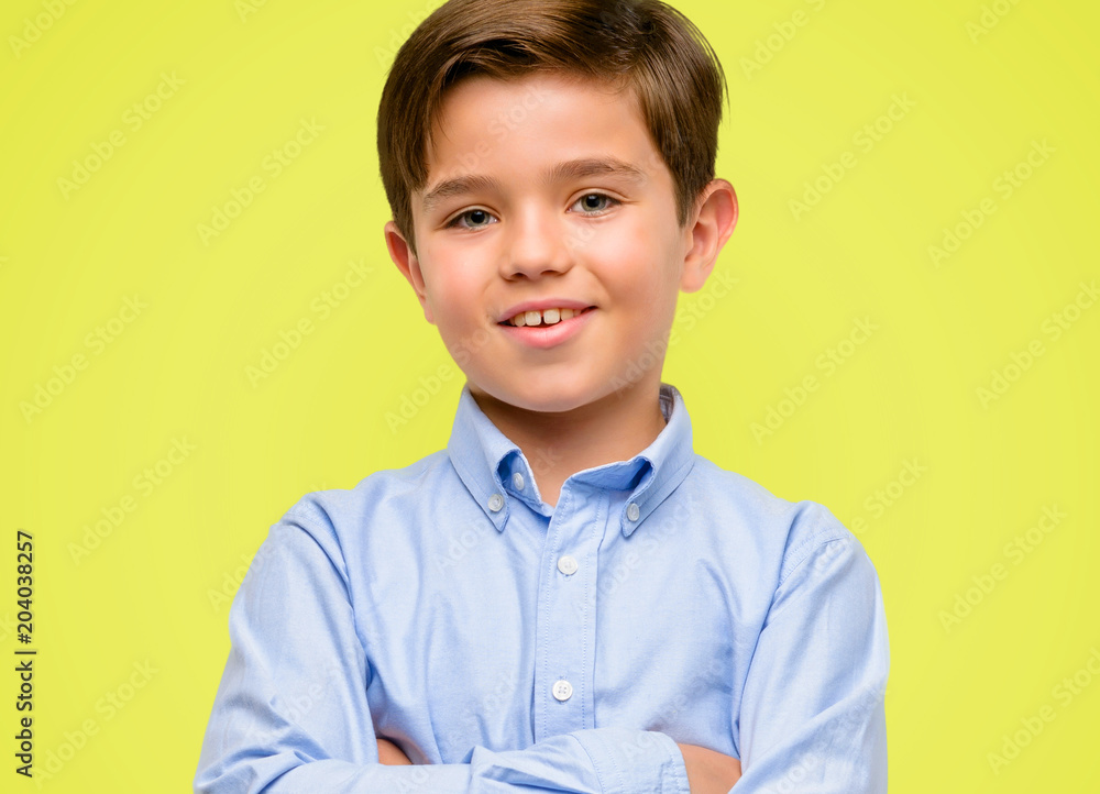 Handsome toddler child with green eyes confident and happy with a big natural smile laughing over yellow background Handsome toddler child with green eyes confident and happy with a big natural smile laughing over yellow background