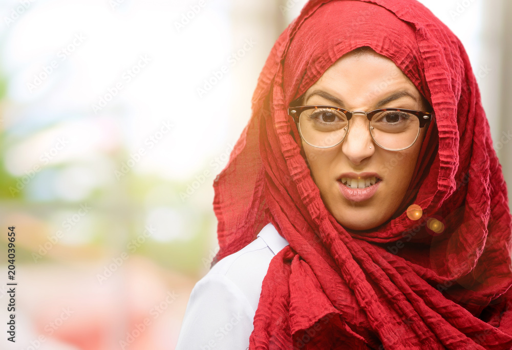 Young arab woman wearing hijab angry and stressful frowns face in dissatisfaction, irritated and annoyed, expressing anger Young arab woman wearing hijab angry and stressful frowns face in dissatisfaction, irritated and annoyed, expressing anger