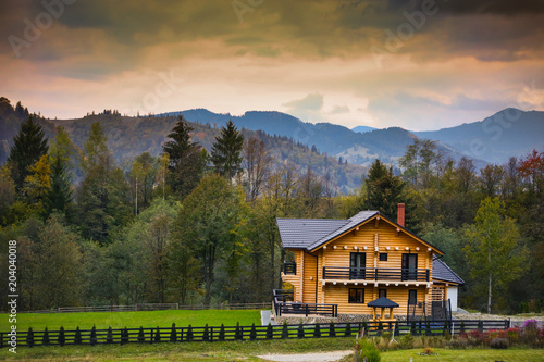 Autumn scenery in Bucovina with wooden cabin at sunset